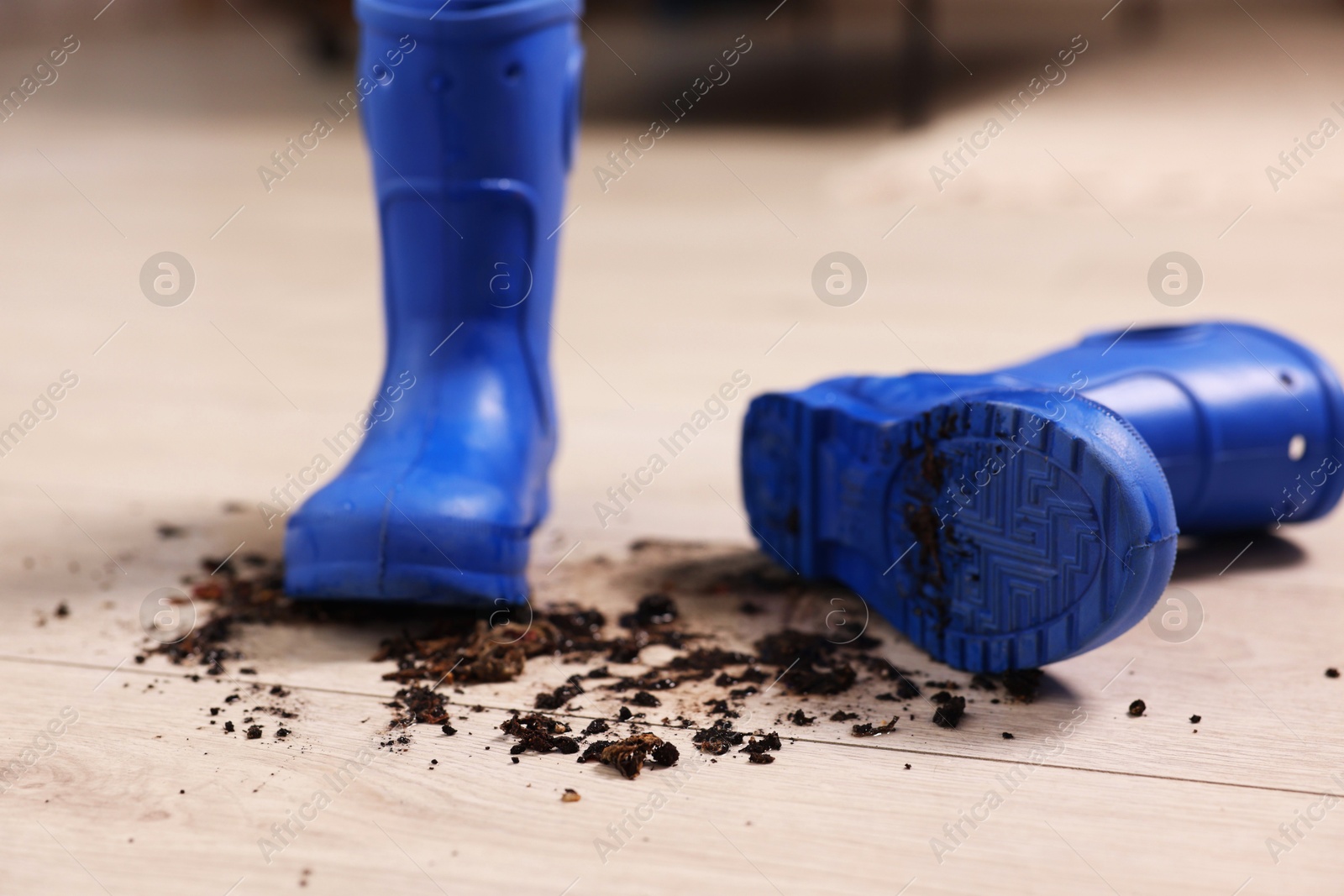 Photo of Rubber boots with mud on wooden floor