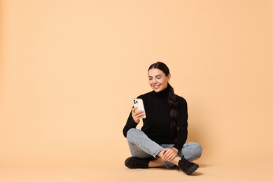 Photo of Smiling woman with smartphone on beige background. Space for text