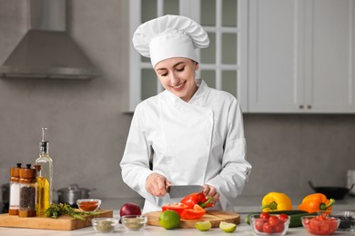 Professional chef cutting pepper at table in kitchen