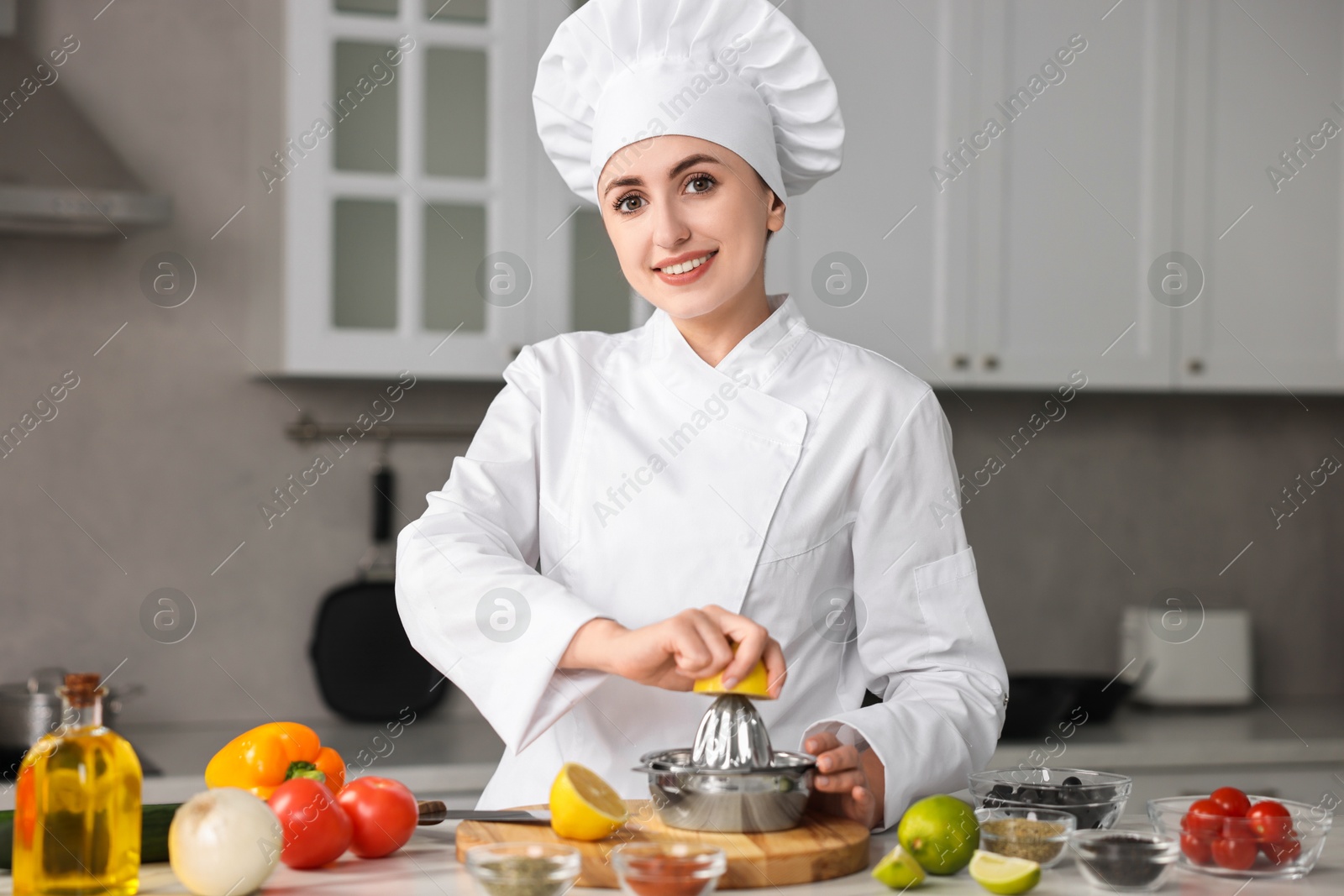 Photo of Woman squeezing juice out of lemon at table in kitchen