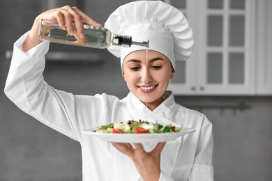 Professional chef pouring oil onto delicious salad in kitchen