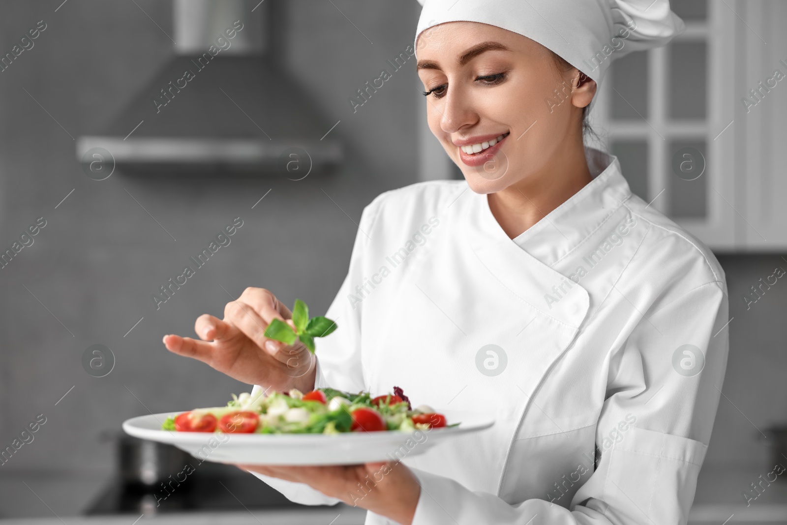 Photo of Professional chef decorating delicious salad with basil in kitchen