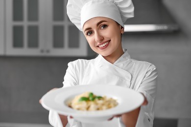 Photo of Professional chef with delicious pasta in kitchen, selective focus