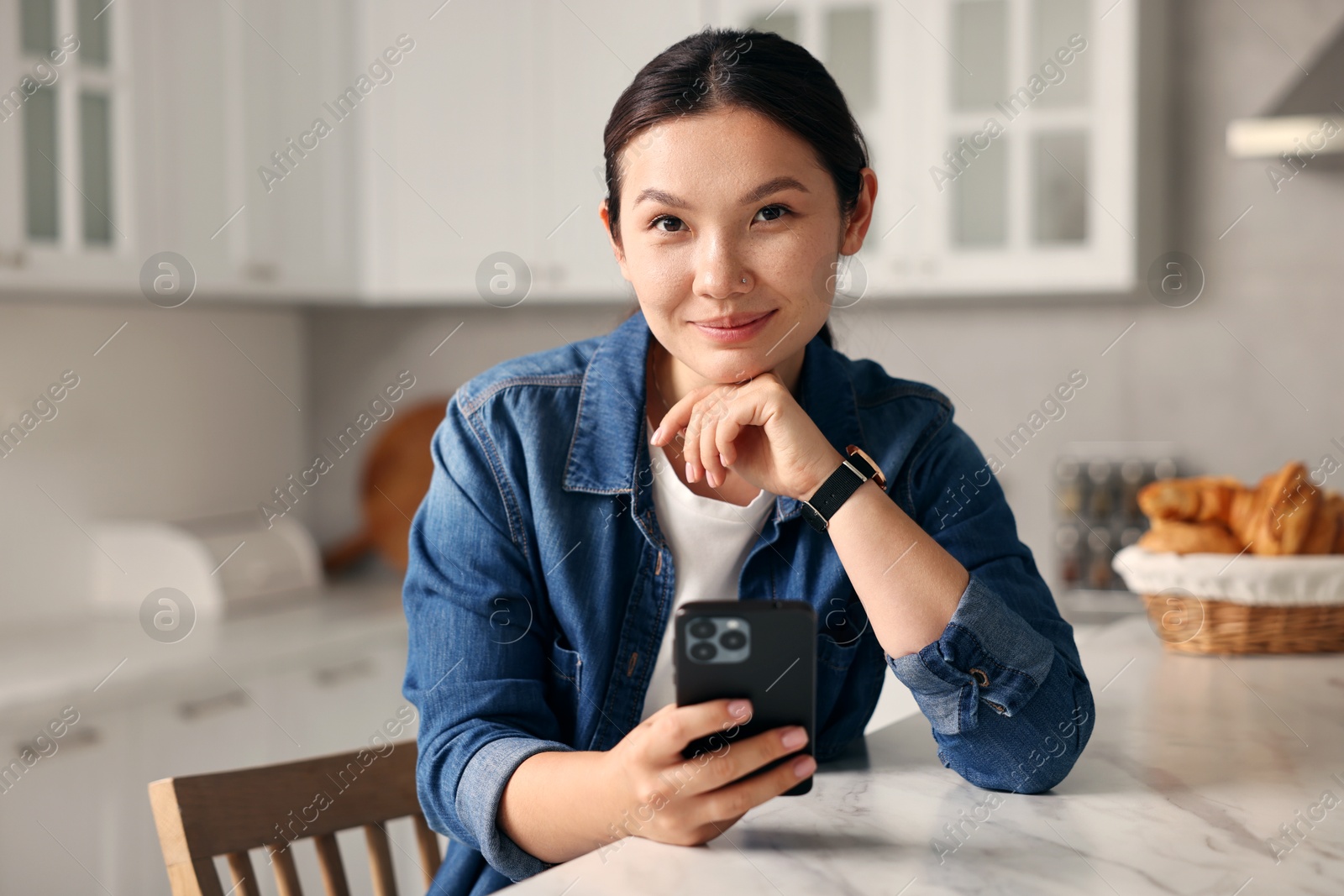 Photo of Portrait of beautiful woman with smartphone in kitchen