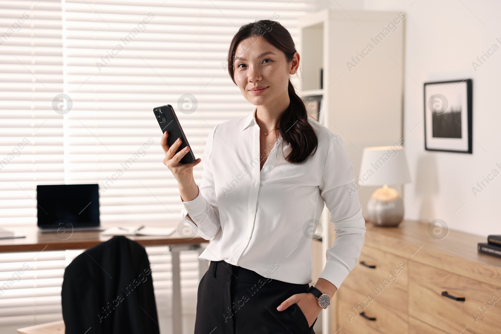 Photo of Portrait of beautiful businesswoman with smartphone in office