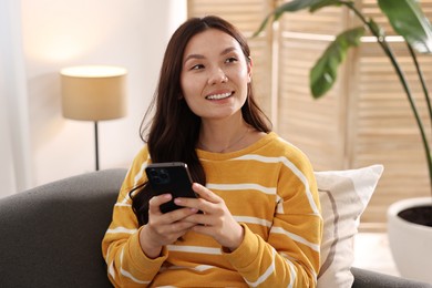 Portrait of smiling woman with smartphone at home