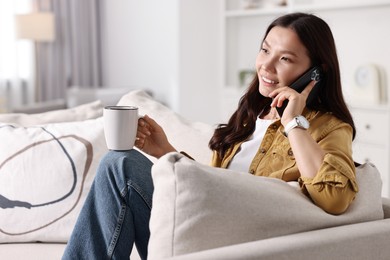 Photo of Smiling woman talking on smartphone at home