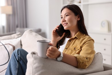 Smiling woman talking on smartphone at home