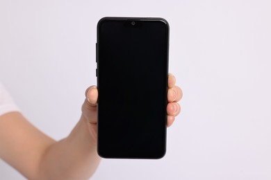 Photo of Woman holding smartphone with blank screen on white background, closeup