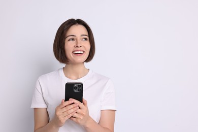 Happy woman with smartphone on white background. Space for text