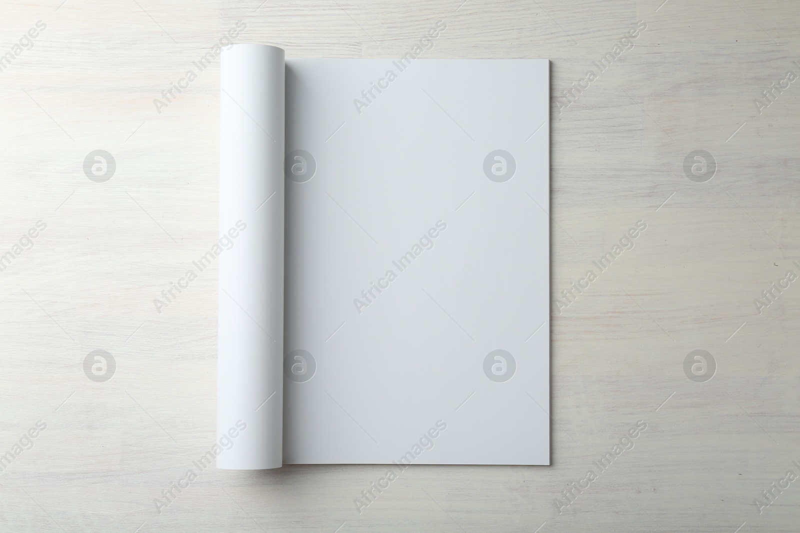 Photo of Open magazine with blank page on light wooden table, top view. Mockup for design