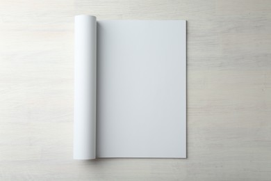 Open magazine with blank page on light wooden table, top view. Mockup for design