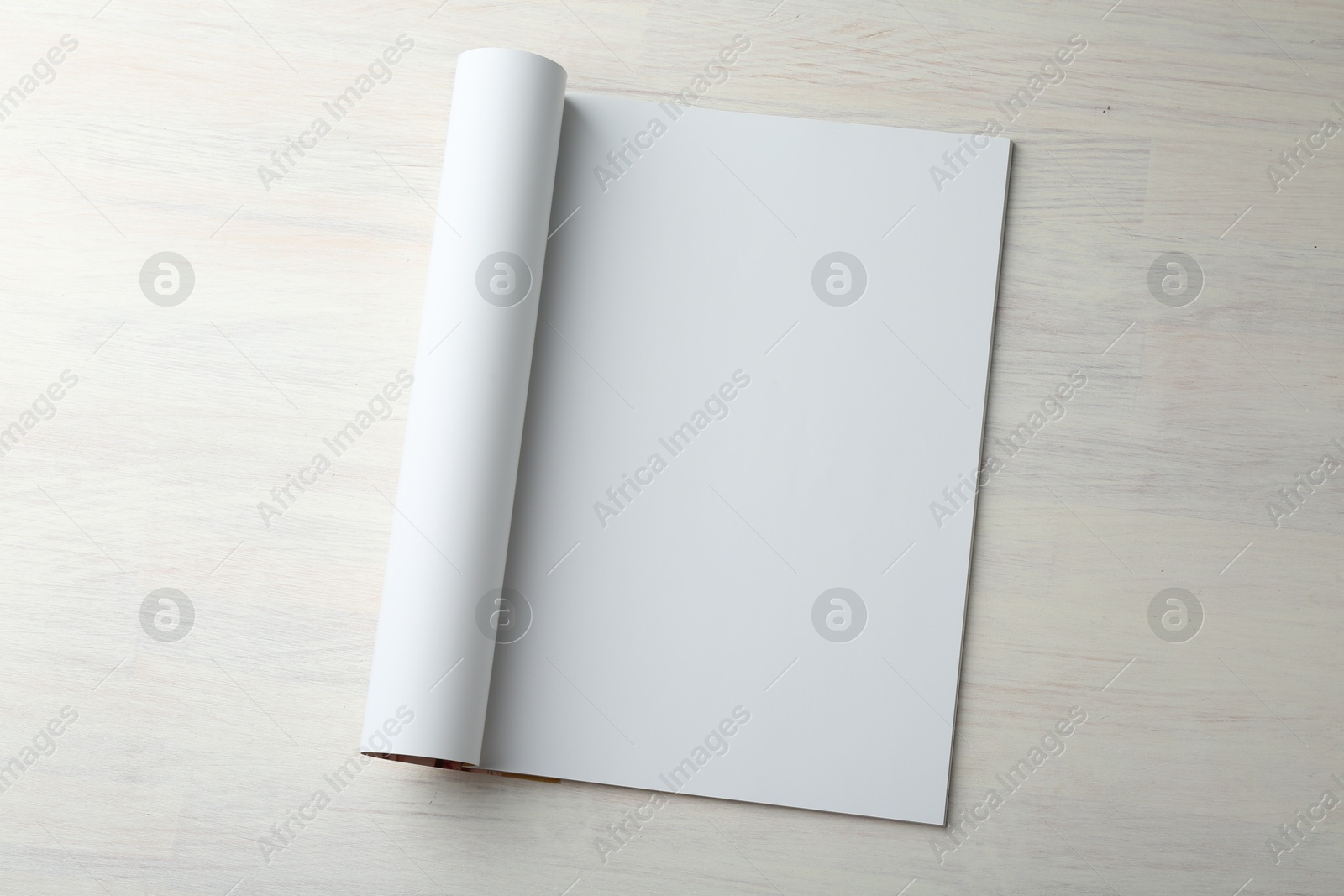 Photo of Open magazine with blank page on light wooden table, top view. Mockup for design