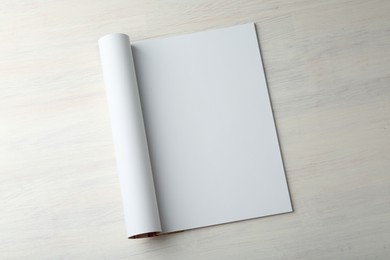 Photo of Open magazine with blank page on light wooden table, top view. Mockup for design