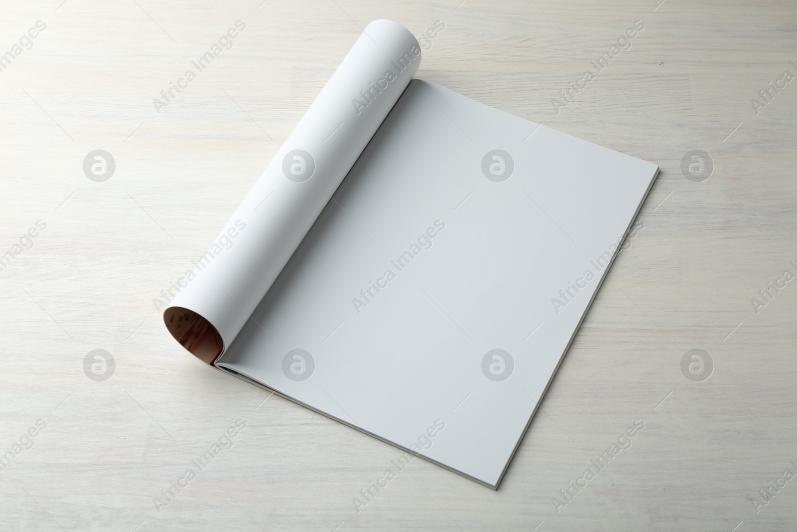 Photo of Open magazine with blank page on light wooden table. Mockup for design