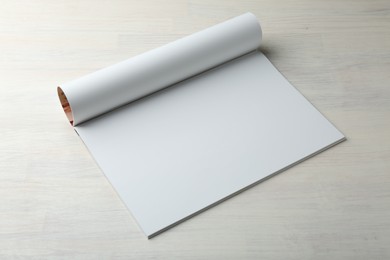 Photo of Open magazine with blank page on light wooden table. Mockup for design