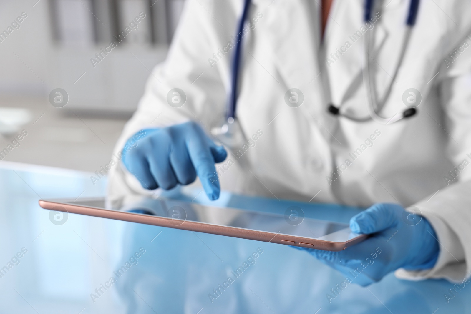 Photo of Doctor with tablet at table in clinic, closeup view