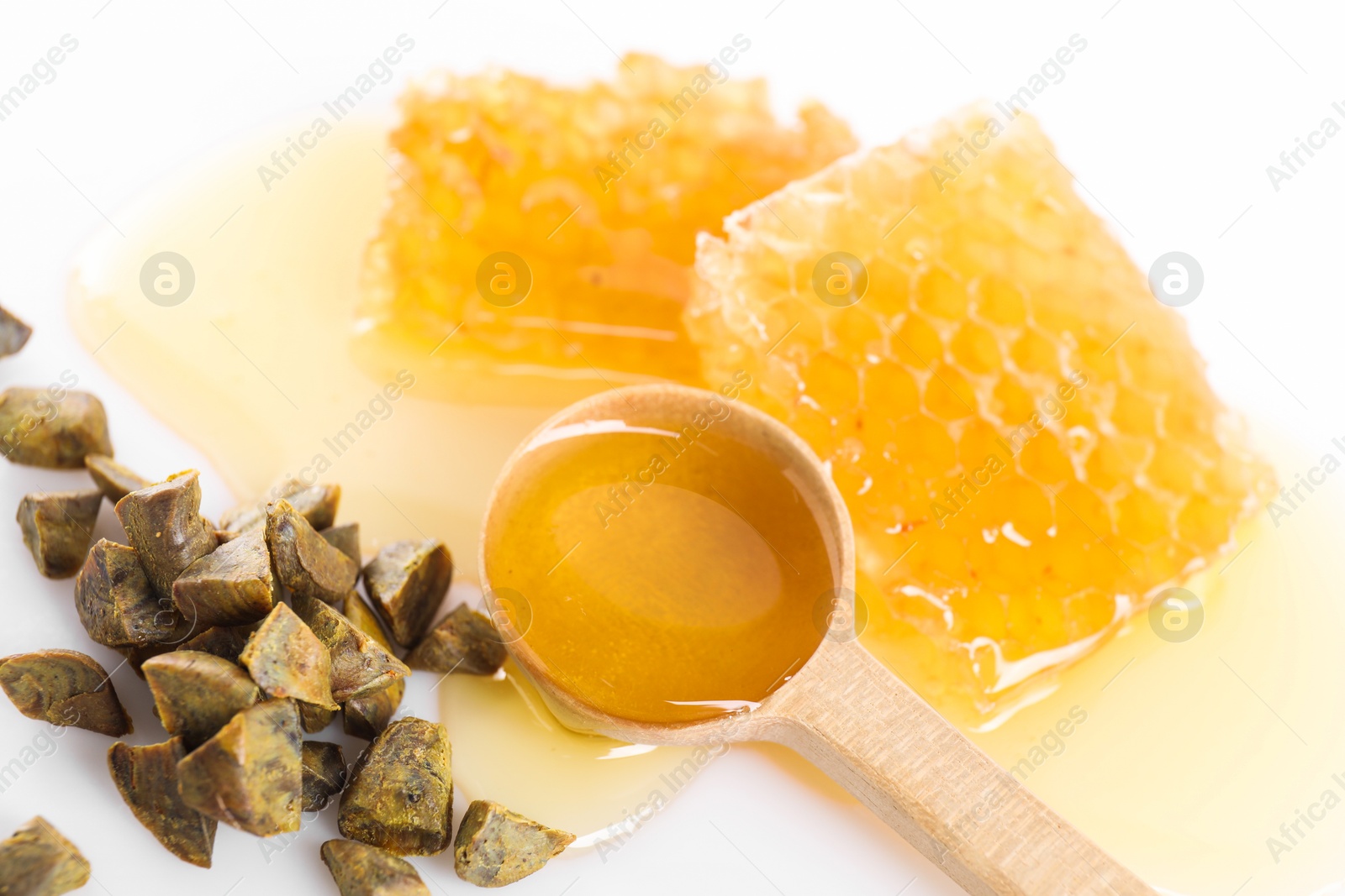 Photo of Sweet honeycombs and propolis granules on white background