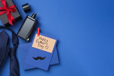 Photo of Greeting card with phrase Happy Father's Day, envelope, bottle of perfume, tie and gift on blue background, flat lay. Space for text