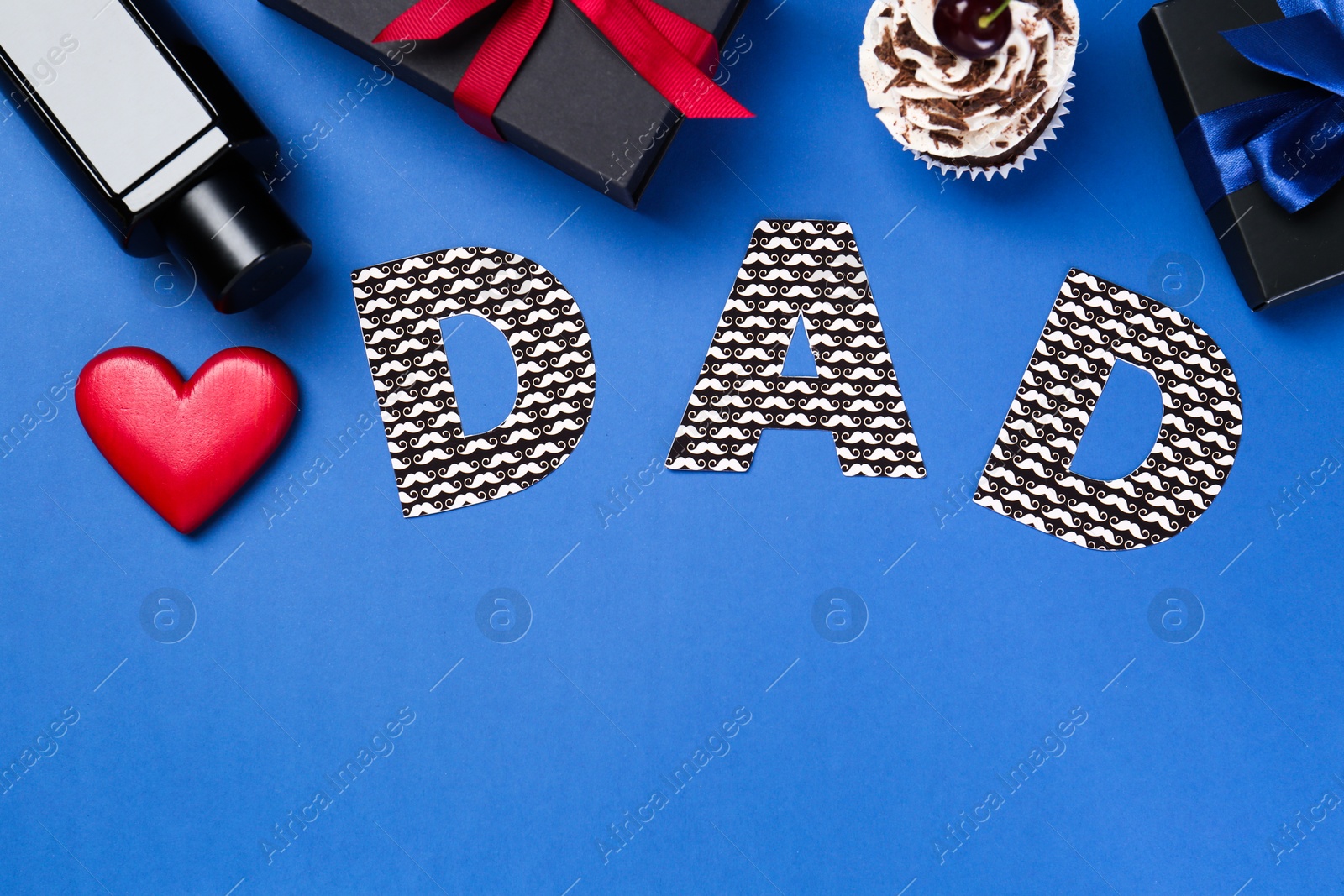 Photo of Happy Father's Day. Word Dad made of paper, decorative heart, perfume, gift boxes and cupcake on blue background, flat lay. Space for text