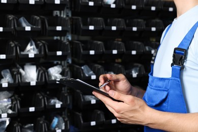 Man with clipboard taking notes in auto store, closeup