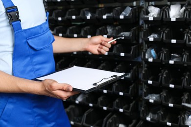 Photo of Man with clipboard and pen in auto store, closeup