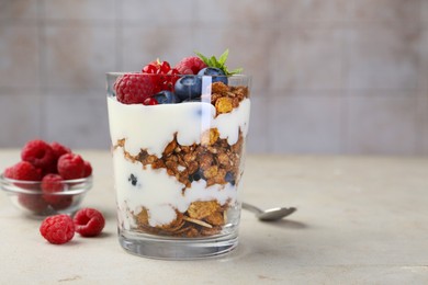 Photo of Tasty yogurt with fresh berries, granola and mint in glass on gray textured table, space for text