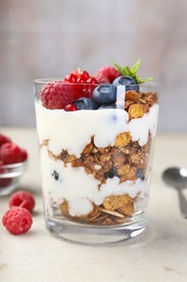 Tasty yogurt with fresh berries, granola and mint in glass on gray textured table