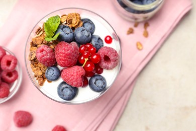 Photo of Tasty yogurt with fresh berries, granola and mint in glass on gray table, top view