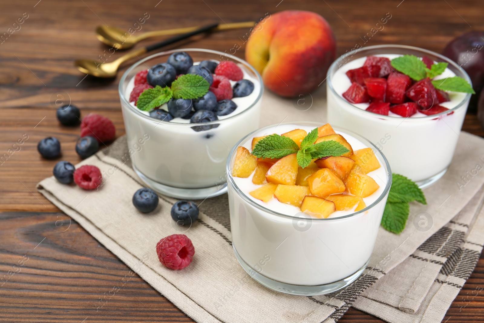 Photo of Tasty yogurt with fresh berries, fruits and mint in glasses on wooden table, closeup