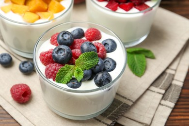 Tasty yogurt with fresh berries, fruits and mint in glasses on table, closeup