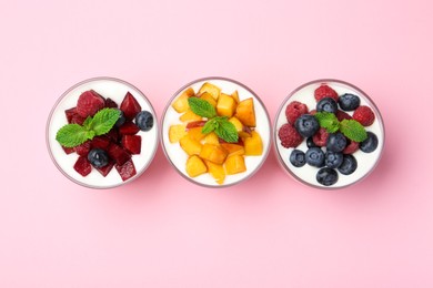 Photo of Tasty yogurt with fresh berries, fruits and mint in glasses on pink background, top view