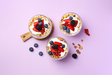 Photo of Tasty yogurt with fresh berries and granola in glasses on violet background, flat lay