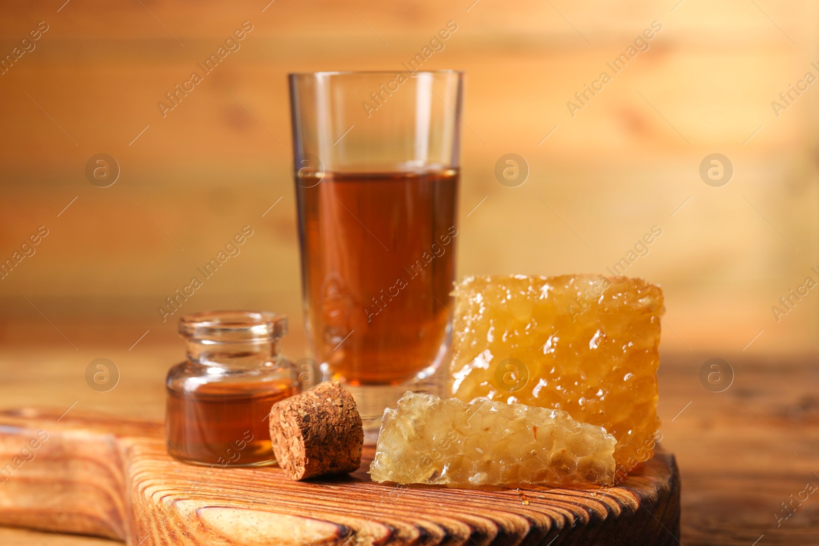 Photo of Natural honey tincture and sweet honeycombs on wooden table, closeup