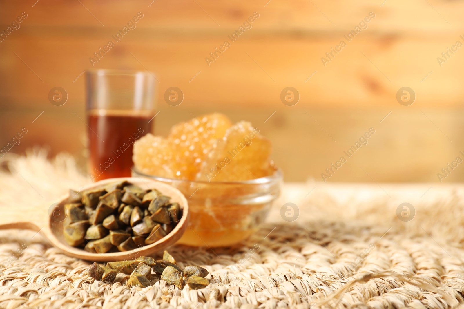 Photo of Spoon with propolis granules, honey tincture and honeycombs on table, closeup. Space for text