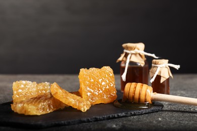 Photo of Honey tincture, dipper and honeycombs on grey textured table, closeup. Alternative medicine