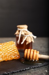 Honeycomb, dipper and honey tincture on grey textured table, closeup. Alternative medicine