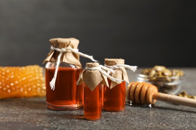 Honey tinctures, dipper and honeycomb on grey textured table, closeup. Alternative medicine