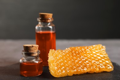 Photo of Honey tinctures and honeycomb on table, closeup. Alternative medicine