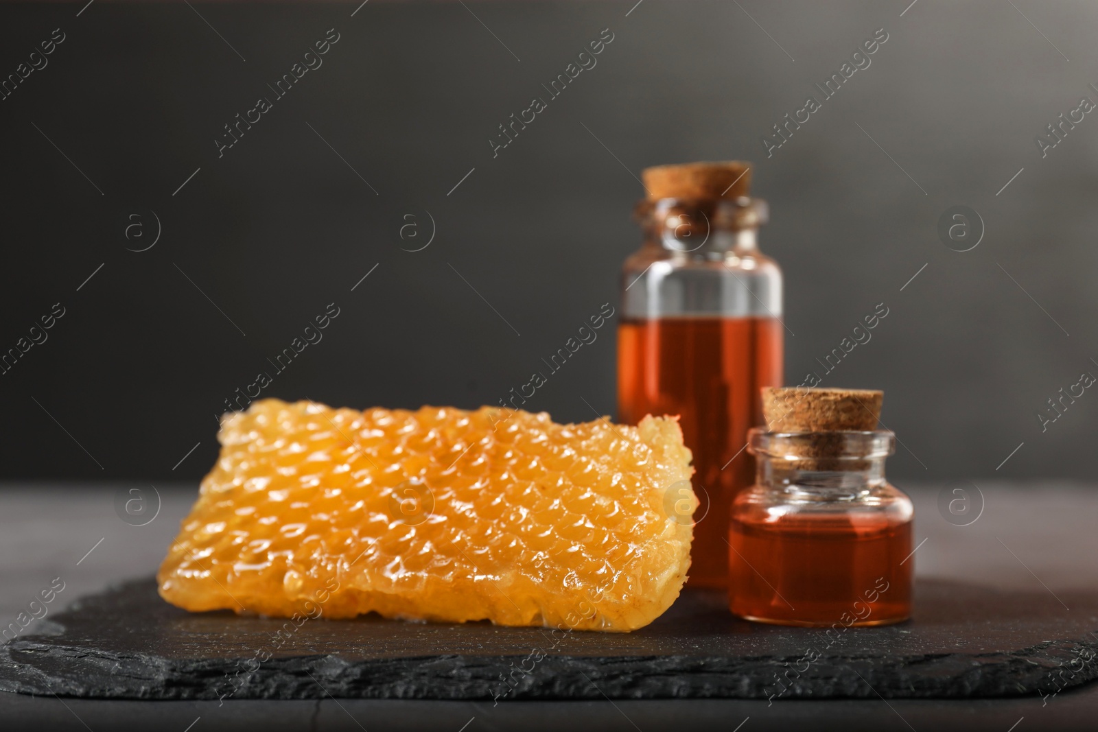 Photo of Honey tinctures and honeycomb on table, closeup. Alternative medicine