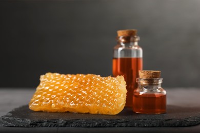 Photo of Honey tinctures and honeycomb on table, closeup. Alternative medicine