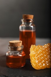 Photo of Honey tinctures and honeycomb on table, closeup. Alternative medicine