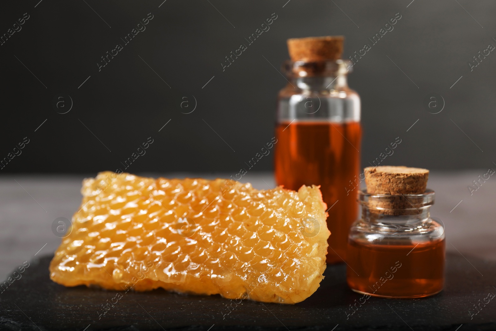 Photo of Honey tinctures and honeycomb on table, closeup. Alternative medicine