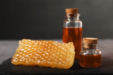 Photo of Honey tinctures and honeycomb on table, closeup. Alternative medicine