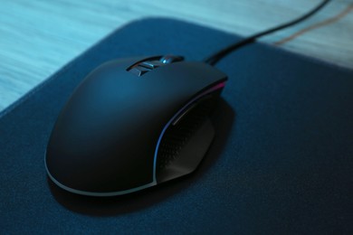 Photo of Computer mouse with mousepad on wooden table, closeup