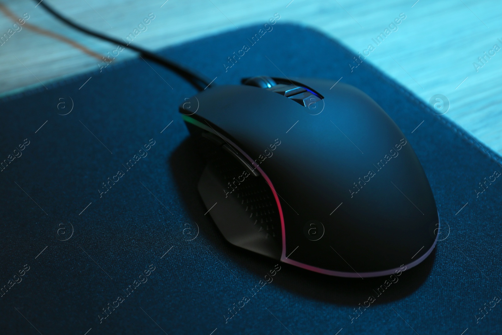 Photo of Computer mouse with mousepad on wooden table, closeup