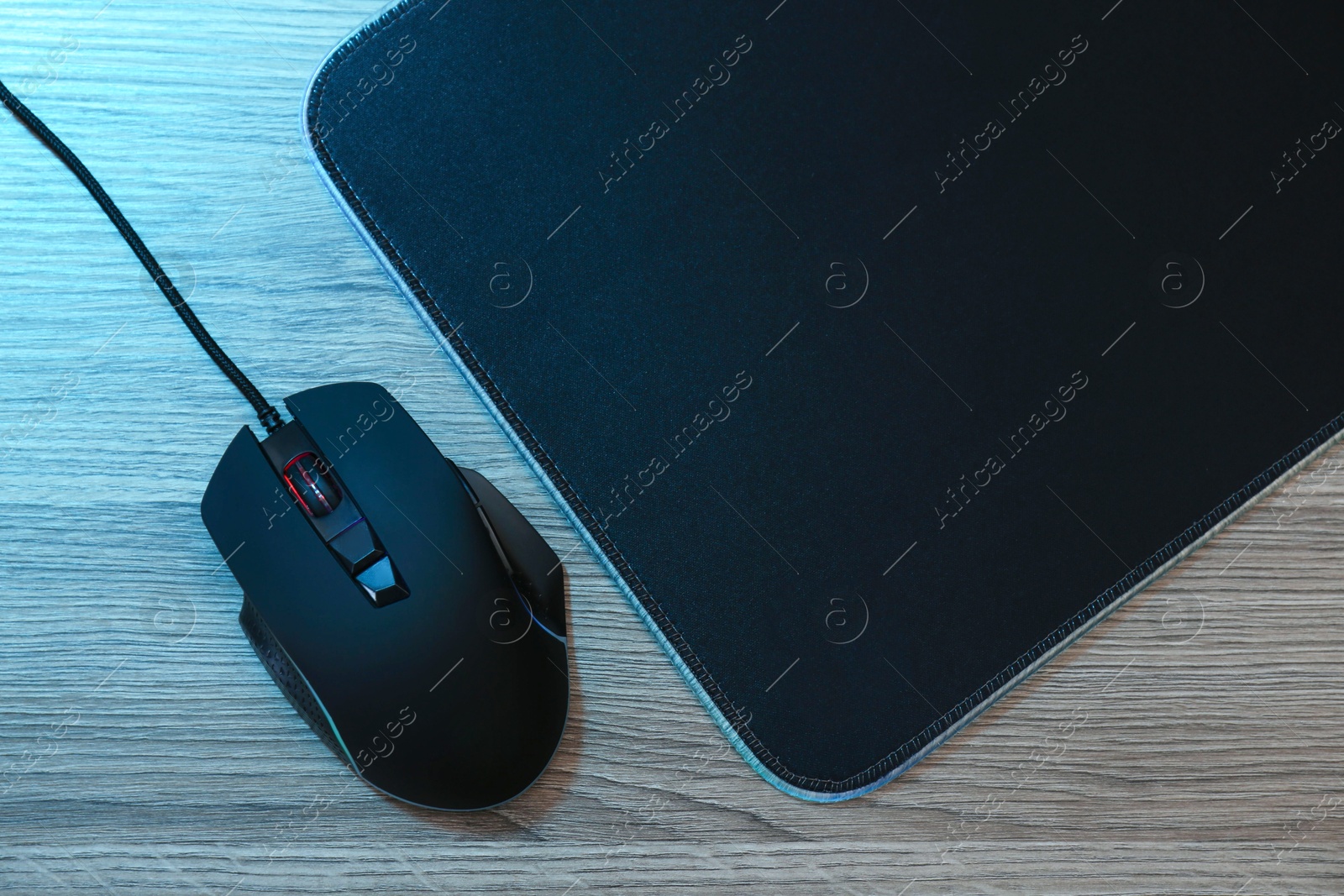 Photo of Computer mouse with mousepad on wooden table, flat lay