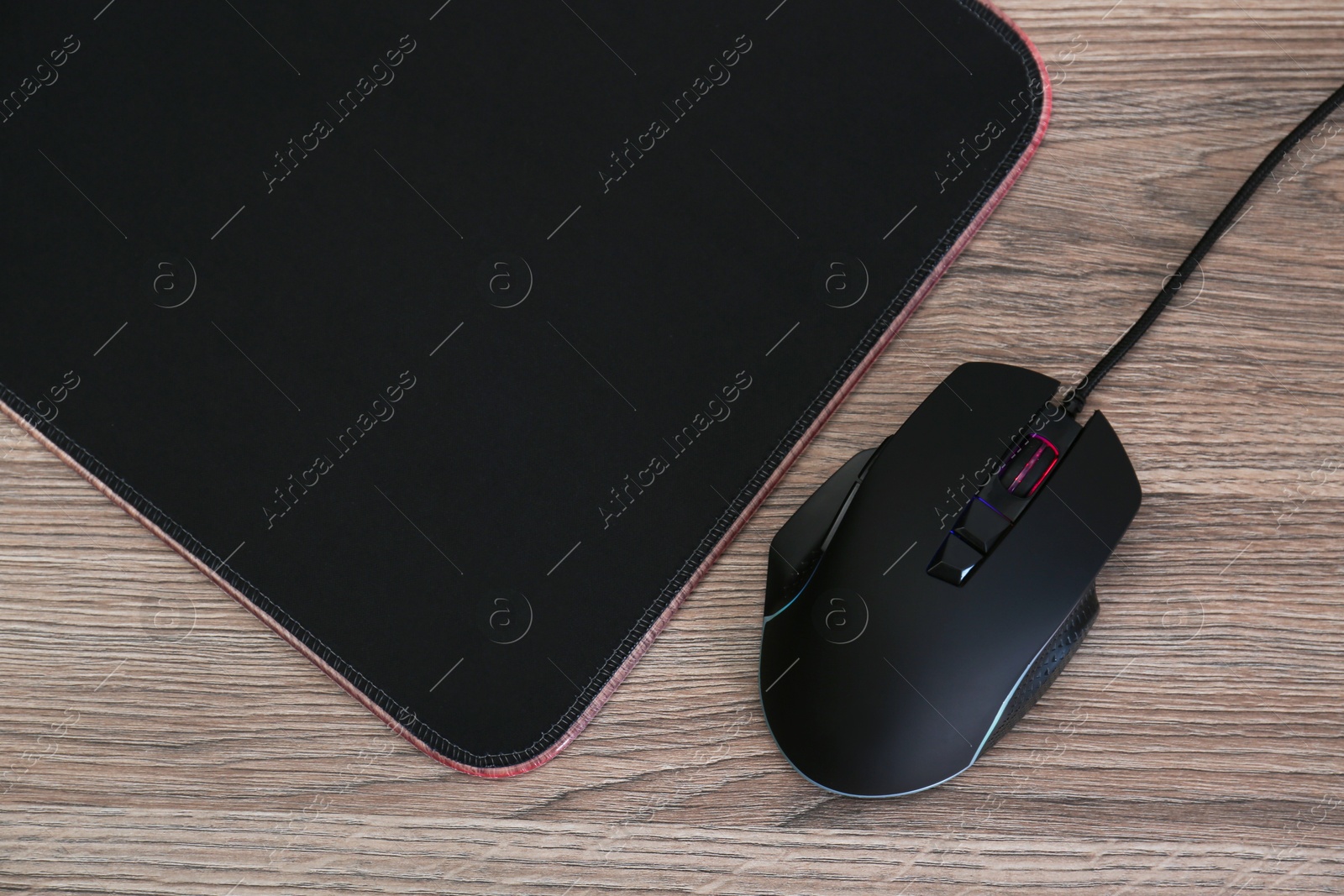 Photo of Computer mouse with mousepad on wooden table, flat lay