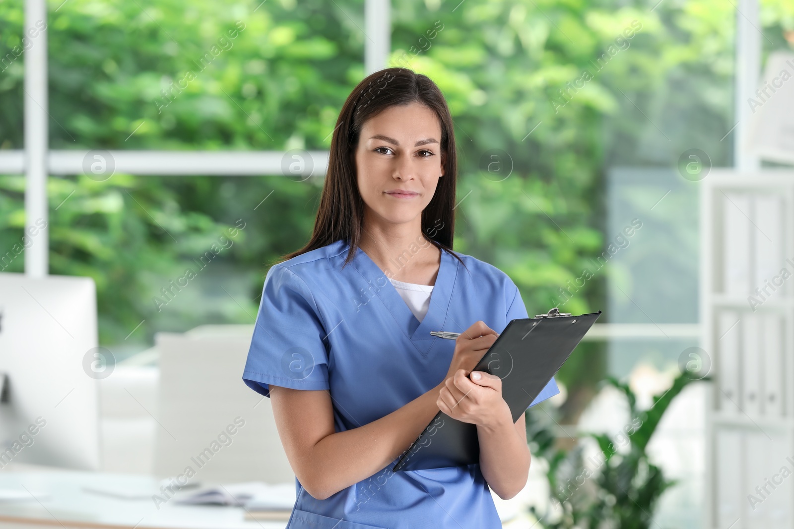 Photo of Beautiful nurse with clipboard in hospital office