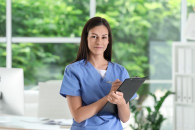 Beautiful nurse with clipboard in hospital office